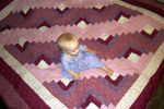 Annabel sitting on her beautiful new quilt from Aunt Dian
