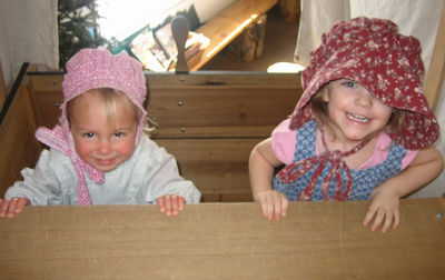 Maia and Annabel playing peek-a-boo in the covered wagon