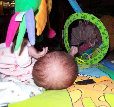 Annabel looking at herself in the mirror on her playmat